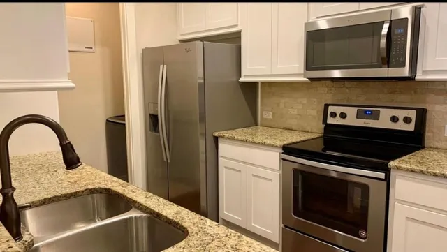 a kitchen with granite countertop a sink stove and microwave