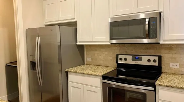 a kitchen with stainless steel appliances white cabinets and a stove top oven