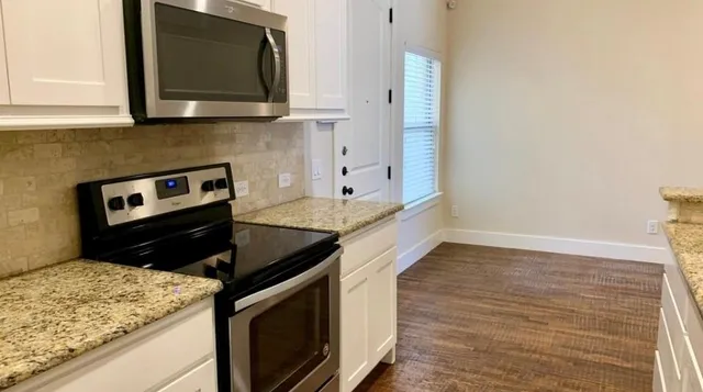 a kitchen with granite countertop a stove and a microwave