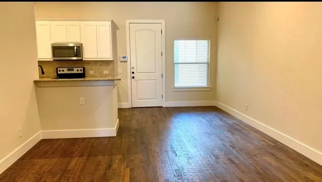a view of a kitchen with wooden floor and electronic appliances