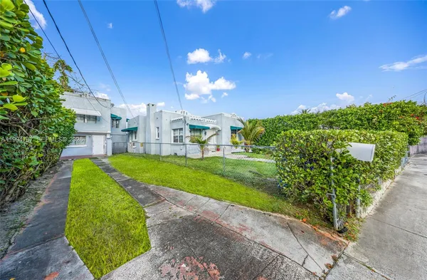 a view of a house with a big yard plants and large trees