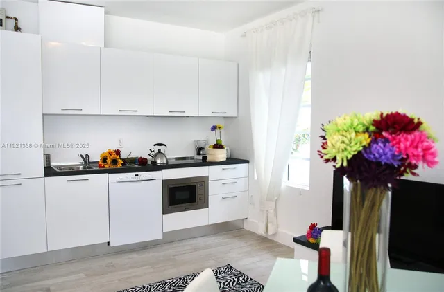 a kitchen with stainless steel appliances white cabinets sink and a refrigerator