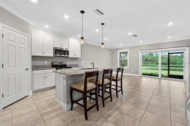 a kitchen with stainless steel appliances a stove a sink a microwave a dining table and chairs