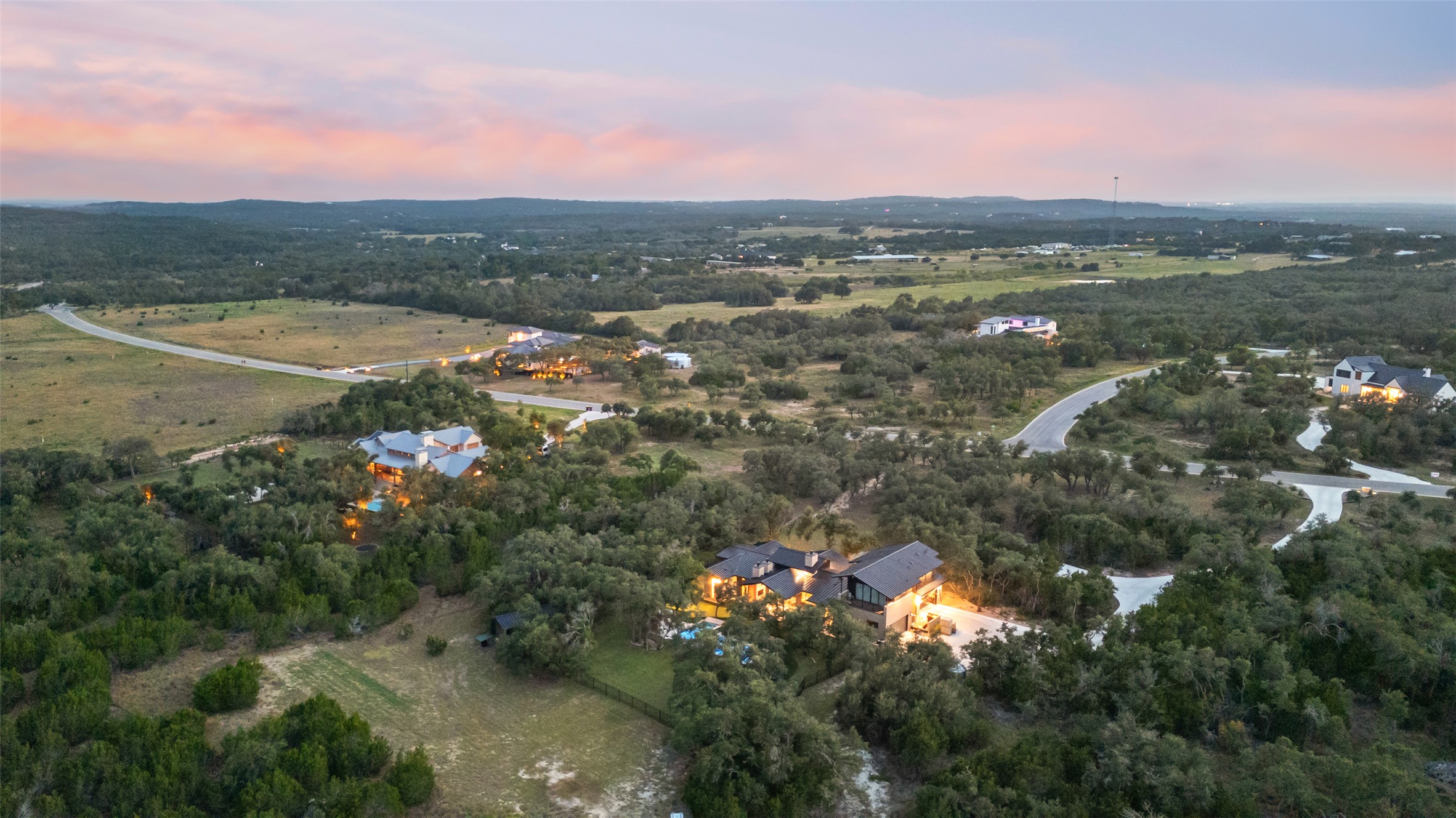 Lot 17 Mesa Rnch Road Dripping Springs, TX 78620 - Photo 6 of 9 A rolling green landscape frames this luxury estate under a twilight sky.