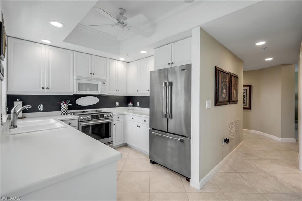 315 Dunes Boulevard, Unit 307 Naples, FL 34110 - Photo 11 of 44 a kitchen with a refrigerator a stove a sink and white cabinets
