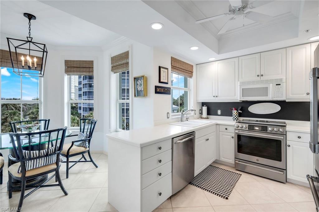 315 Dunes Boulevard, Unit 307 Naples, FL 34110 - Photo 14 of 44 a kitchen with a stove a sink and chairs