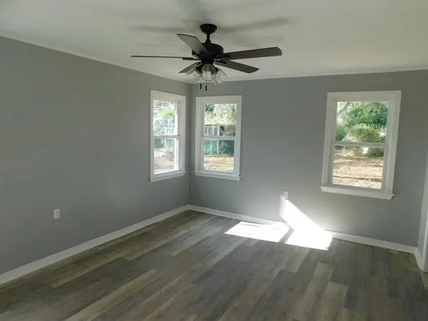 a view of an empty room with wooden floor and a window