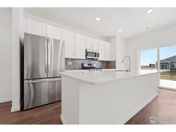 a kitchen with stainless steel appliances granite countertop a refrigerator sink and white cabinets