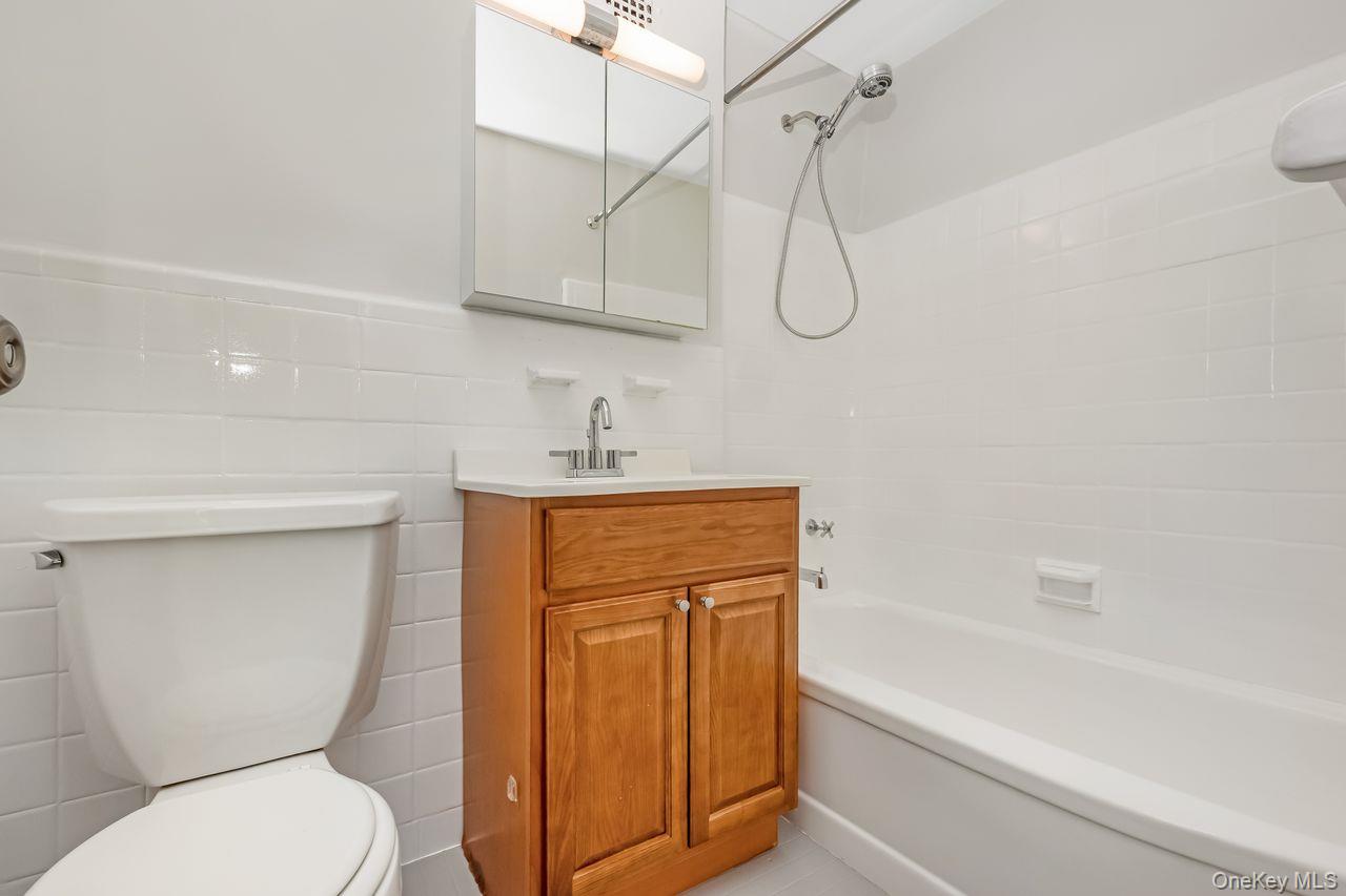 98-50 63rd Drive, Unit 1F Queens, NY 11374 - Photo 13 of 15 a bathroom with a granite countertop toilet sink and shower