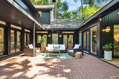 a view of a backyard with table and chairs potted plants and large tree