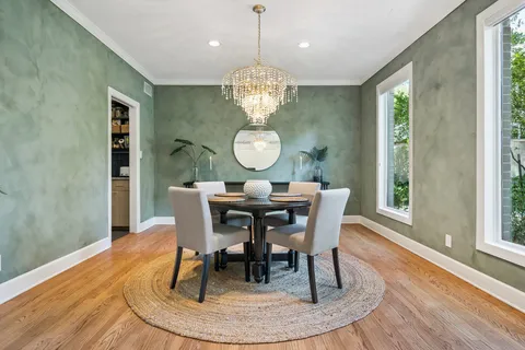 a dining room with wooden floor a chandelier a wooden table and chairs
