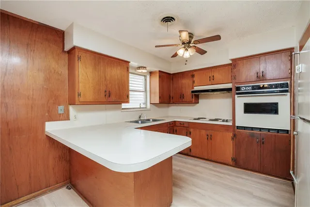 a kitchen with stainless steel appliances a sink a stove a refrigerator cabinets and wooden floor