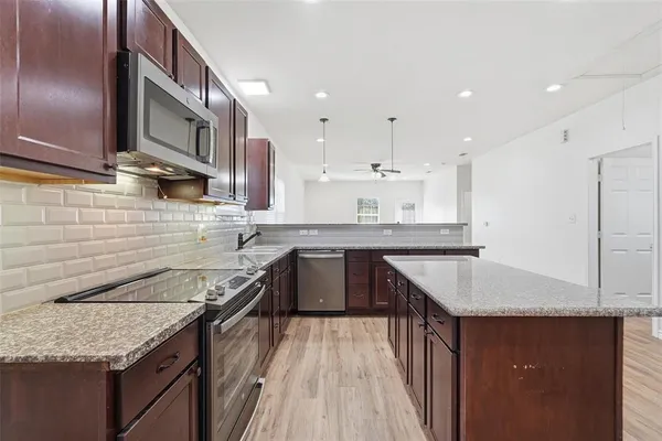 a kitchen with granite countertop kitchen island stainless steel appliances a sink stove and cabinets