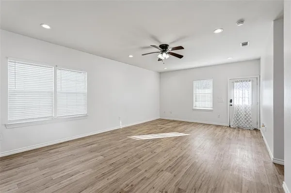 a view of an empty room with a window and wooden floor
