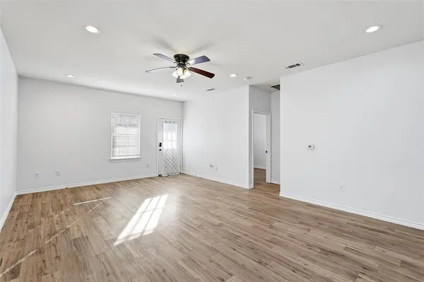 a view of empty room with wooden floor and fan