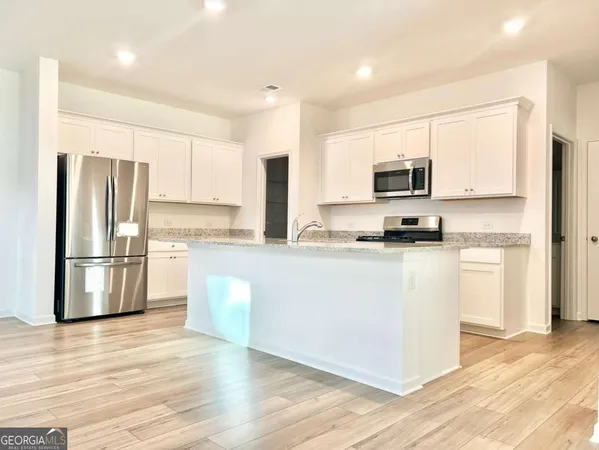 a kitchen with kitchen island a refrigerator and a stove top oven