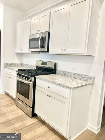 a kitchen with granite countertop white cabinets and stainless steel appliances