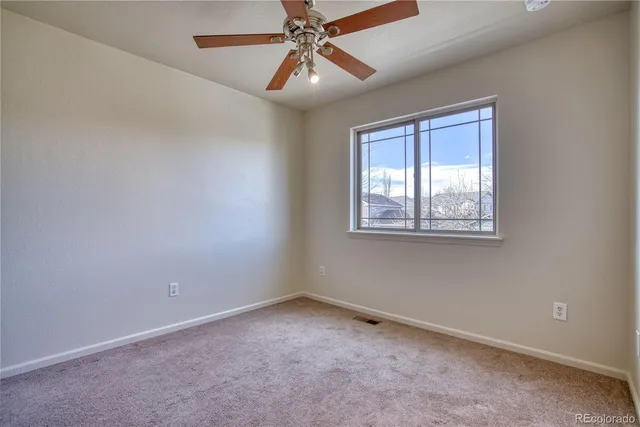 an empty room with chandelier fan and windows