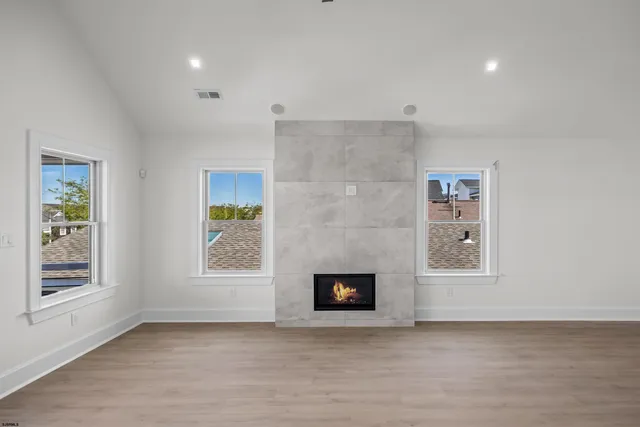 an empty room with windows and fireplace