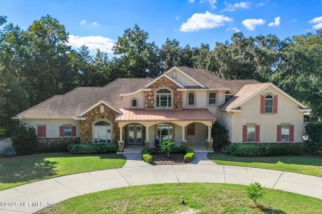 an aerial view of a house with swimming pool and trees