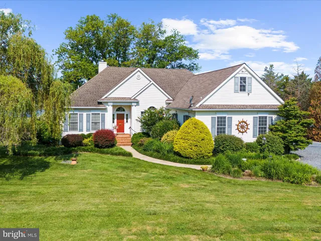 a front view of a house with a garden and trees