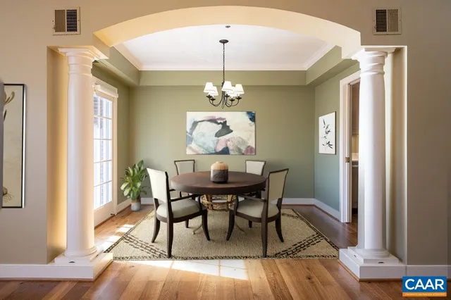 a dining room with chandelier and wooden floor