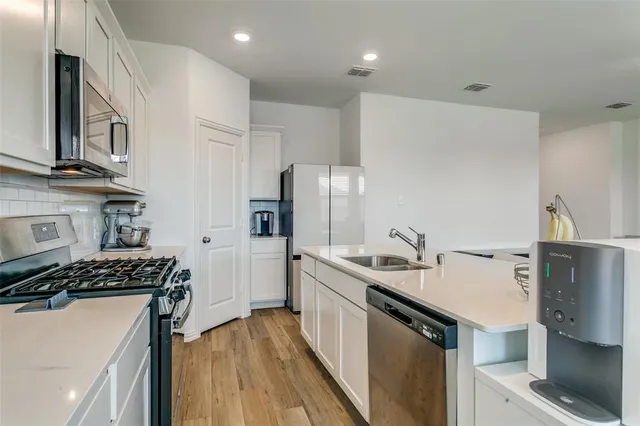 a kitchen with stainless steel appliances a sink a stove a microwave and wooden cabinets