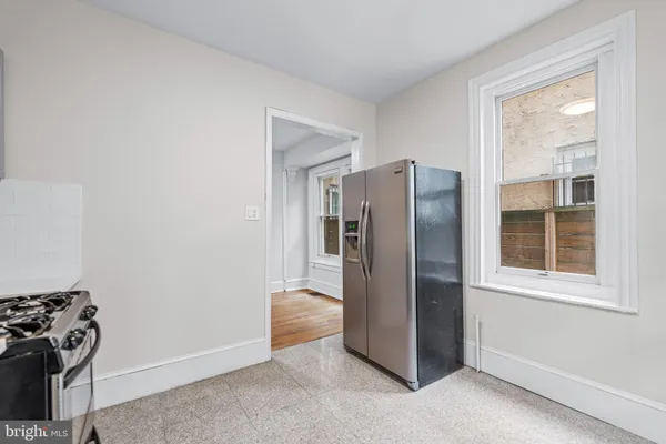 a view of a refrigerator in kitchen and an empty room