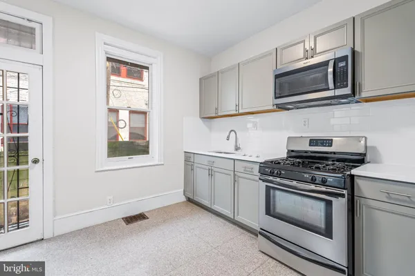 a kitchen with stainless steel appliances granite countertop white cabinets a stove top oven and sink