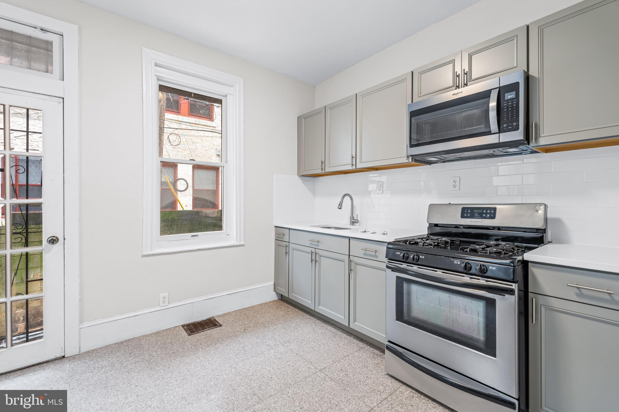 2303 Christian Street, Unit 1 Philadelphia, PA 19146 - Photo 6 of 21 a kitchen with stainless steel appliances granite countertop white cabinets a stove top oven and sink