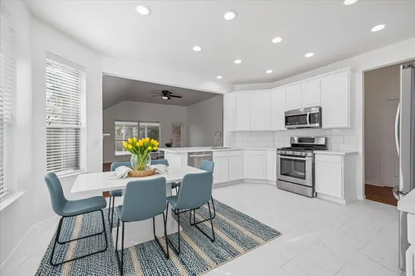 a kitchen with a sink stainless steel appliances and dining table