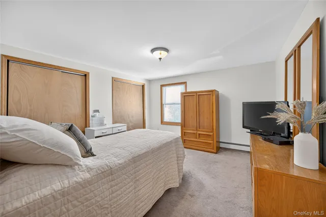 a bedroom with a bed dresser and a flat tv screen