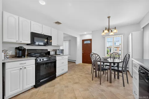 a kitchen with stainless steel appliances granite countertop a stove top oven a sink a dining table and chairs