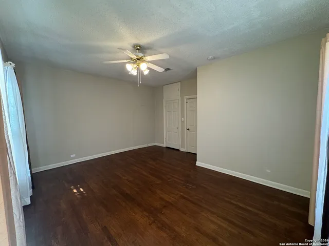 an empty room with wooden floor and fan