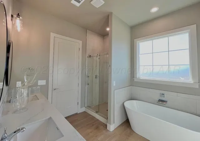 a bathroom with a tub a window and a glass door shower