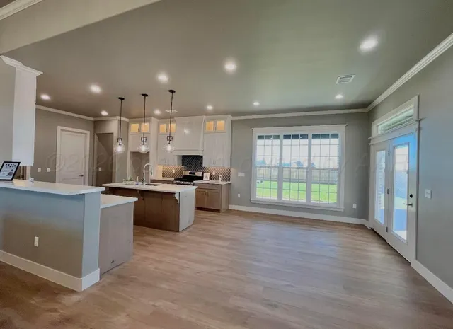 a large kitchen with stainless steel appliances granite countertop a large counter top a stove a sink and a refrigerator