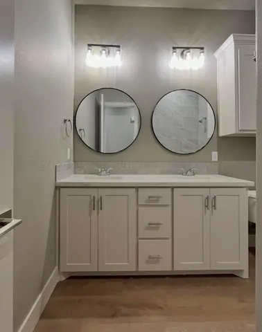 a bathroom with a granite countertop double vanity sink and a mirror