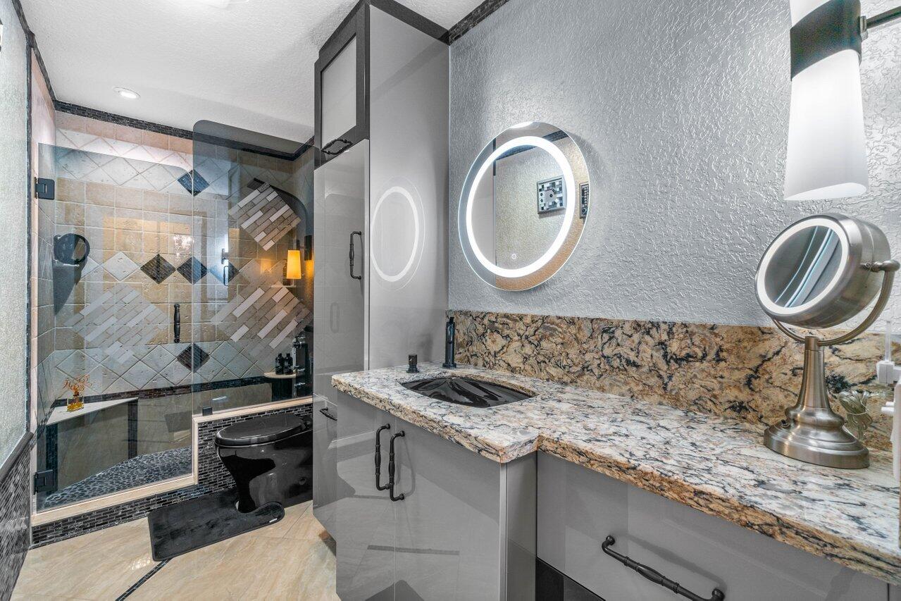294 Northwest 69th Street Boca Raton, FL 33487 - Photo 25 of 39 a bathroom with a granite countertop sink a mirror and a shower