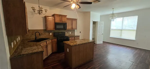 a kitchen with stainless steel appliances granite countertop a stove a sink and a microwave