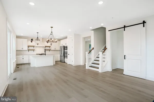 a view of a kitchen with stainless steel appliances granite countertop a sink a stove a refrigerator and island with wooden floor