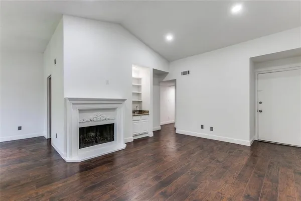 an empty room with wooden floor and fireplace