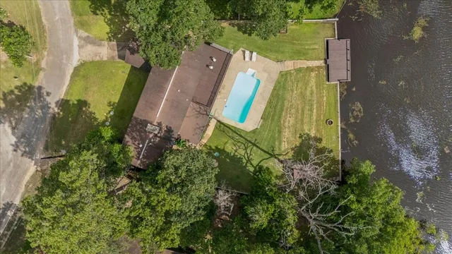 an aerial view of a house with outdoor space and trees all around