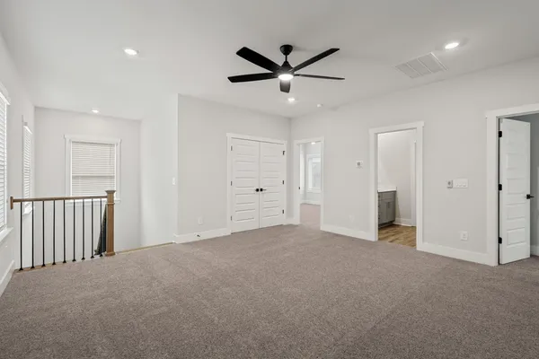 a view of a livingroom with a ceiling fan & windows