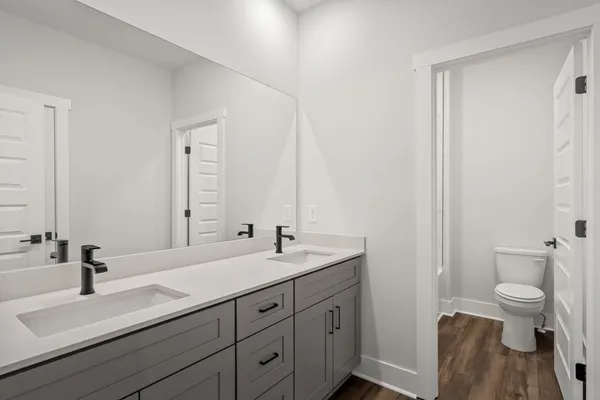 a bathroom with a double vanity sink toilet and a mirror