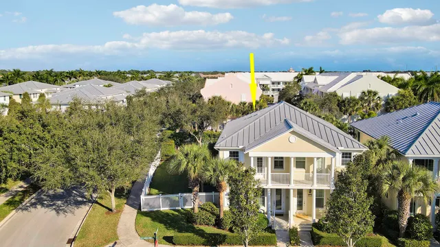 a view of a white house next to a yard with plants and lake view