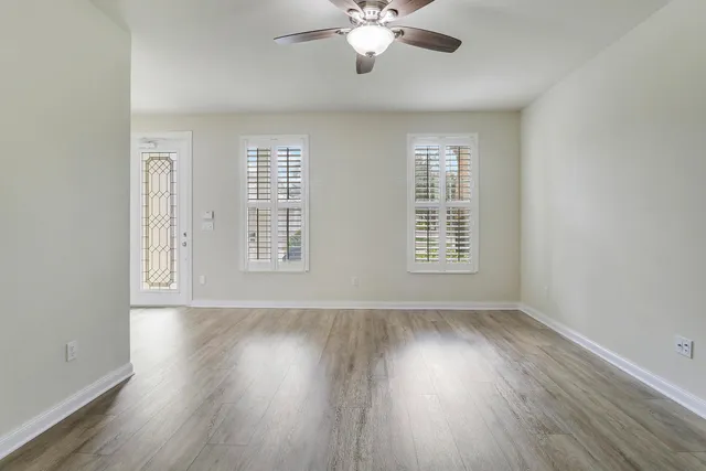 a view of an empty room with wooden floor and a window