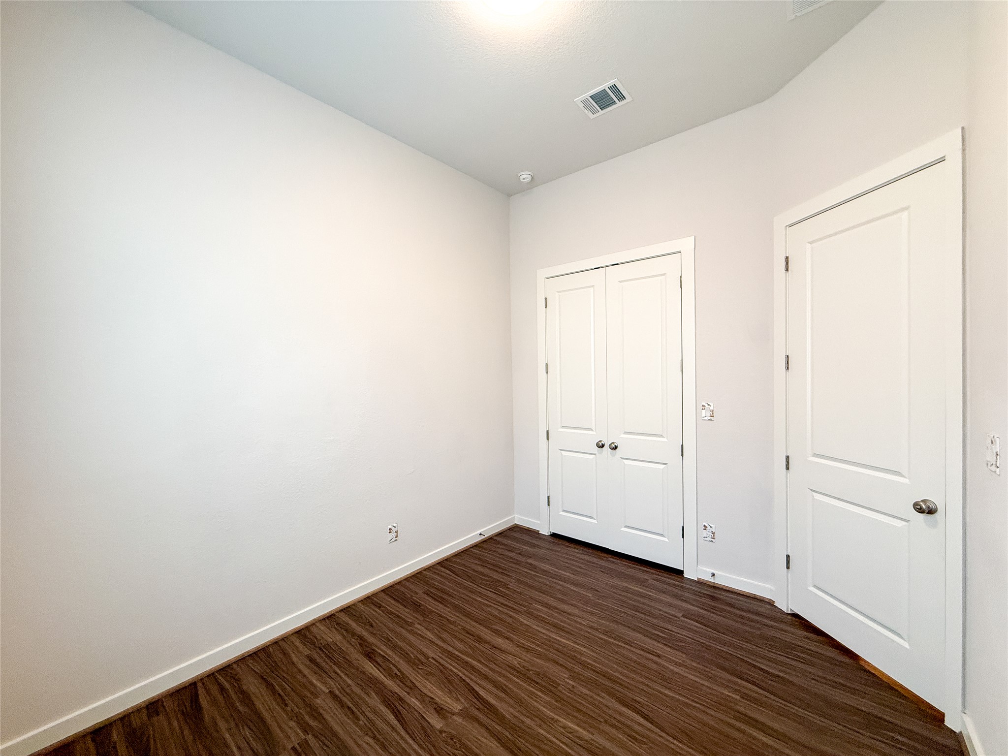 249 Heartleaf Road San Marcos, TX 78666 - Photo 26 of 38 Rich wood flooring grounds this versatile room, featuring two pristine white doors and understated lighting.