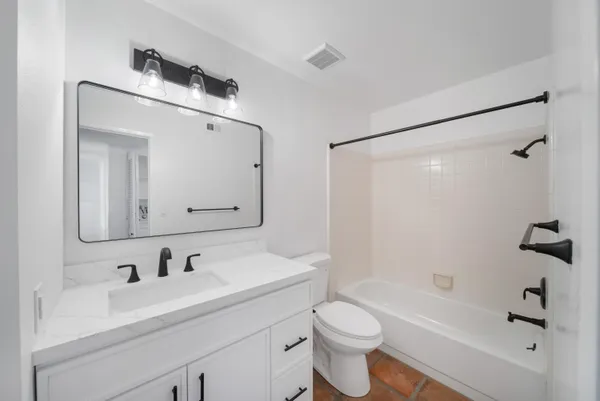 a bathroom with a bathtub shower sink vanity and toilet