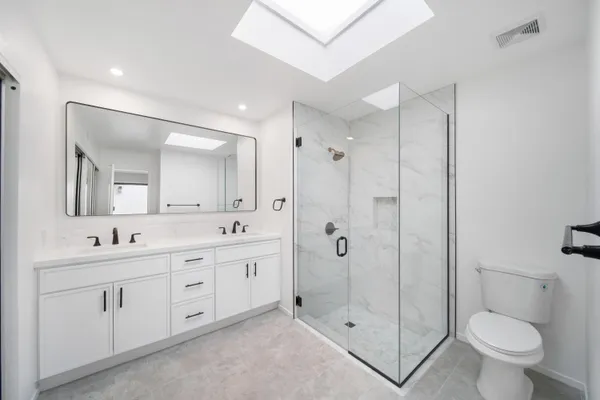 a bathroom with a double vanity sink toilet mirror and shower