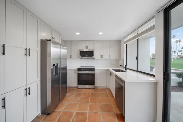 a kitchen with stainless steel appliances granite countertop a refrigerator a sink a stove with cabinets